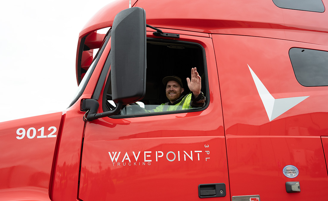 Driver waving from cab of truck